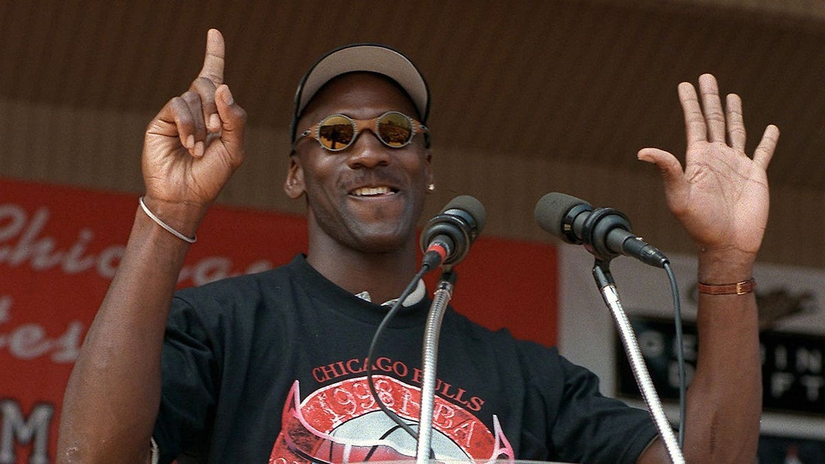 Michael Jordan holds up six fingers while addressing a crowd at Grant Park in Chicago.