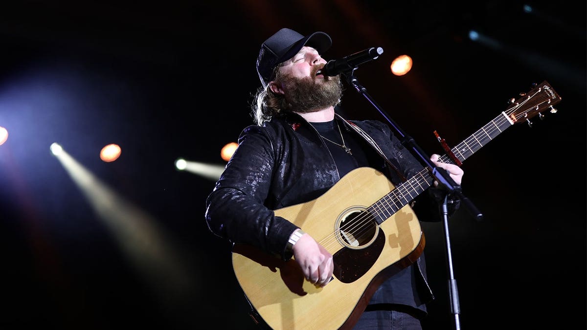 Nate Smith strums guitar on stage.