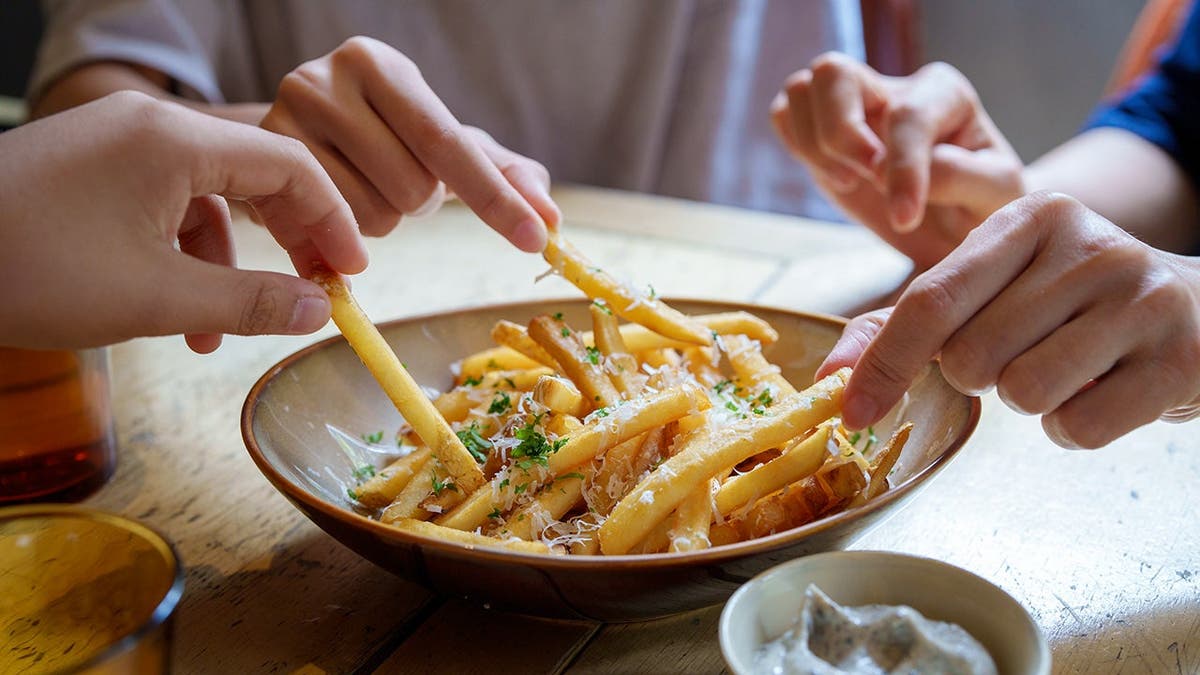 Some people eat French fries from a bowl.