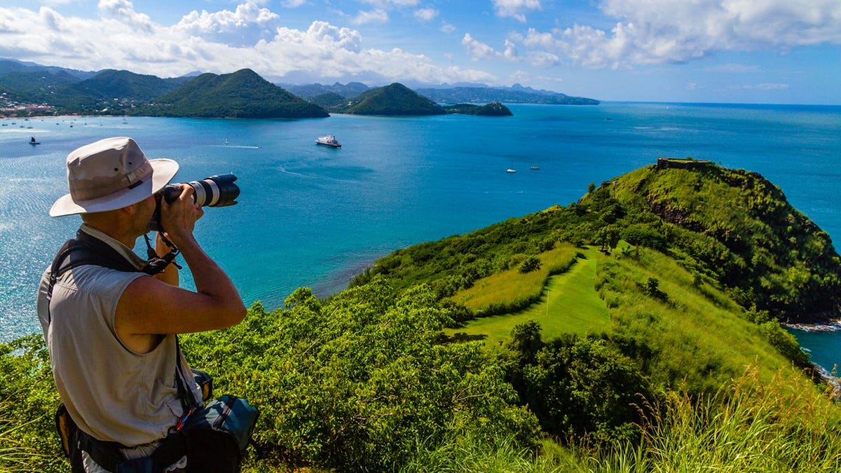 Photographer takes a picture on a hilltop at Pigeon Island National Park.