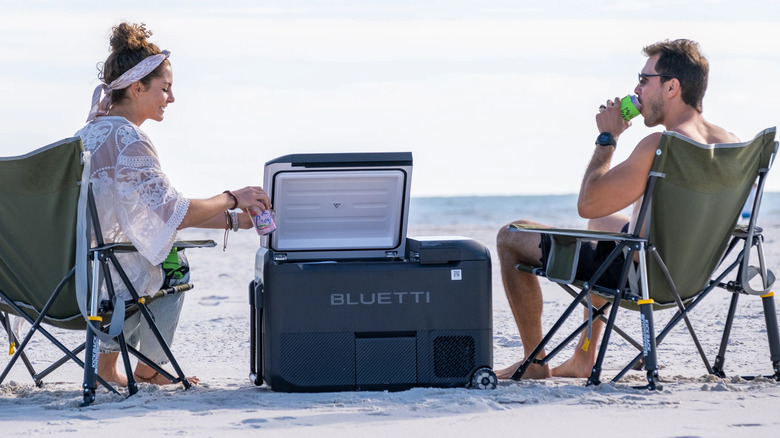 A Bluetti Multicolor with its lid open between two people on a beach