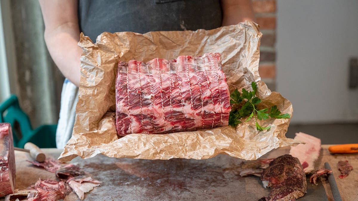 A butcher holds a piece of prime beef.