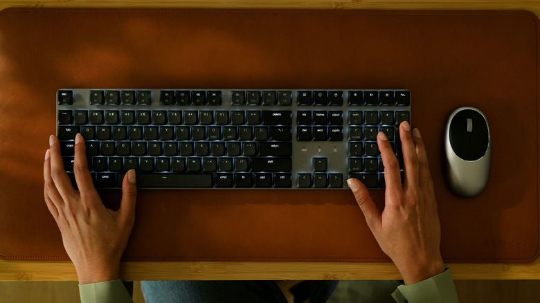 A pair of hands using the Satechi SM3 keyboard, with its backlight turned on