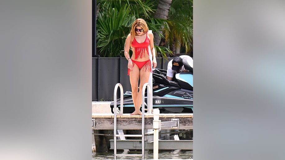 Shakira looking into the ocean as she prepares to jump in.