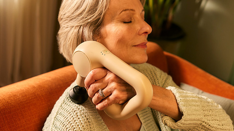 A person using the Theragun Therabody Relief massage gun on their shoulder.