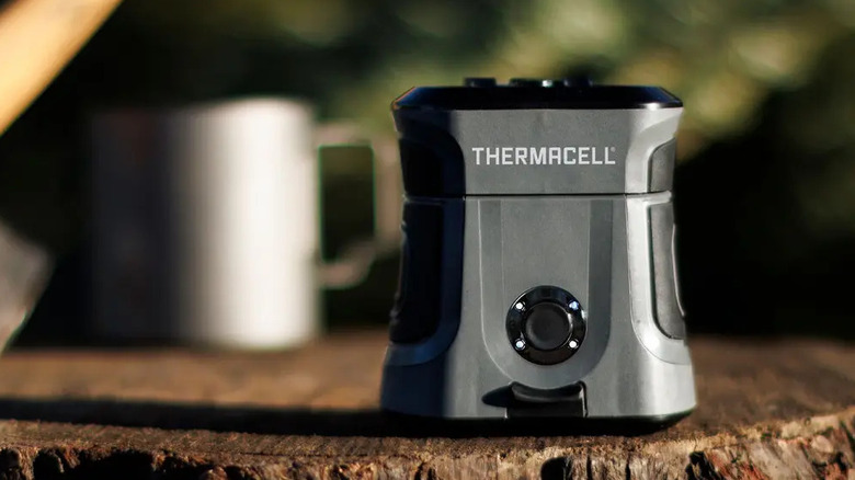 The Thermacell EX90 mosquito repellent placed outdoors on a tree stump.