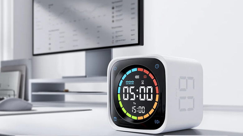 The white Ticktime TK3 Pomodoro Timer Cube on a desk, next to a monitor and mouse