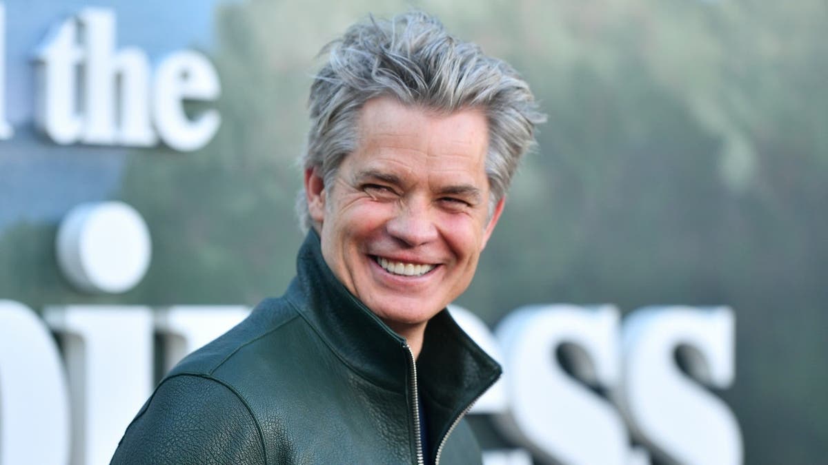Timothy Olyphant stands on the red carpet