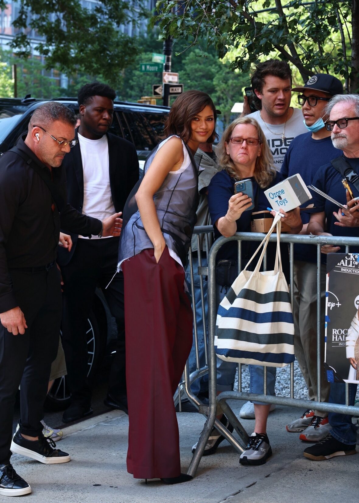 Zendaya in a gray top and burgundy pants.