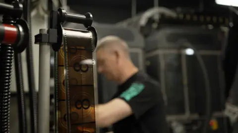 A strip of IMAX 70mm film in the foreground with countdown numbers. A man works behind it.