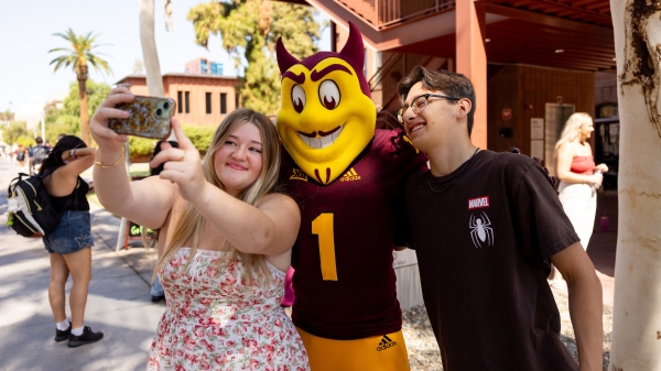 The Sparky mascot takes a selfie with two ASU students