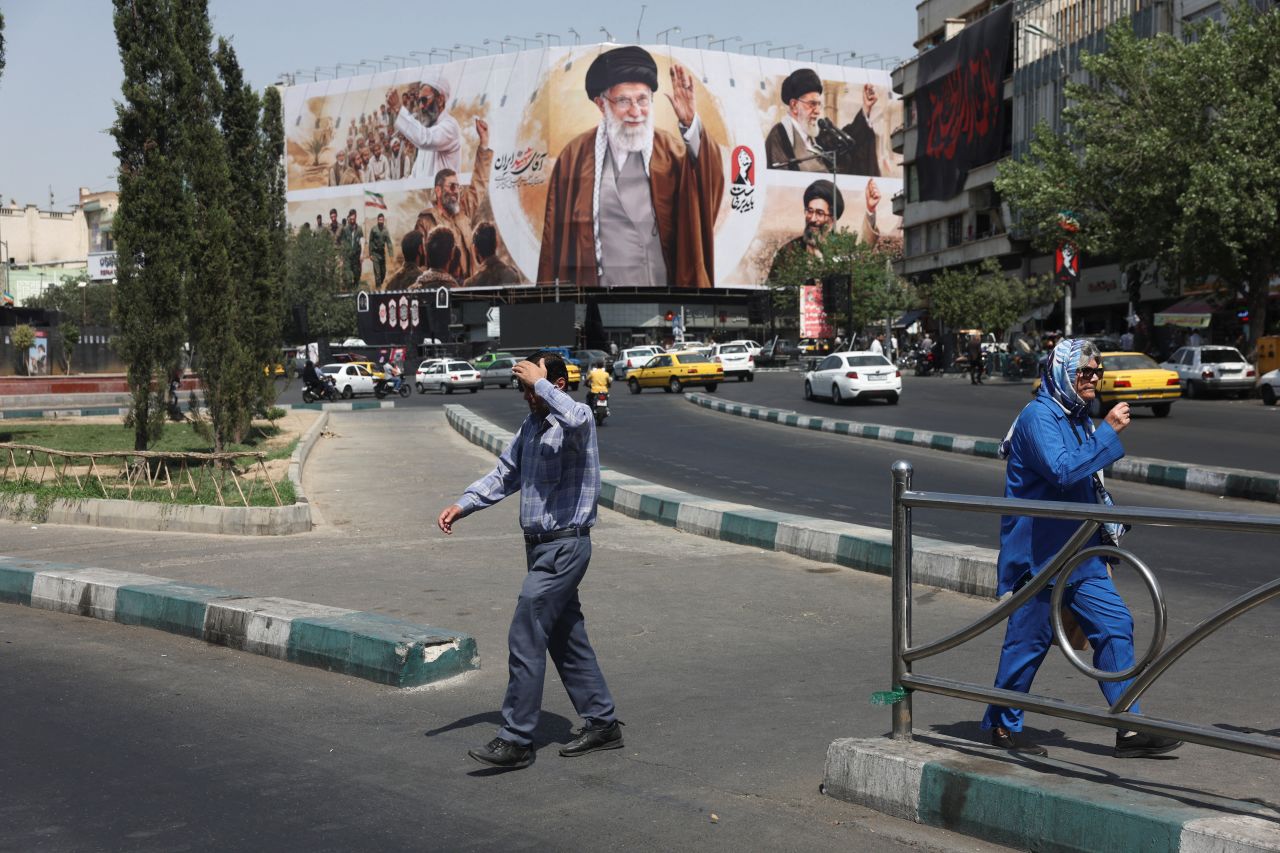 People walk past a billboard featuring images of Iran's late Supreme Leader Ayatollah Ali Khamenei in Tehran, Iran, on July 13.