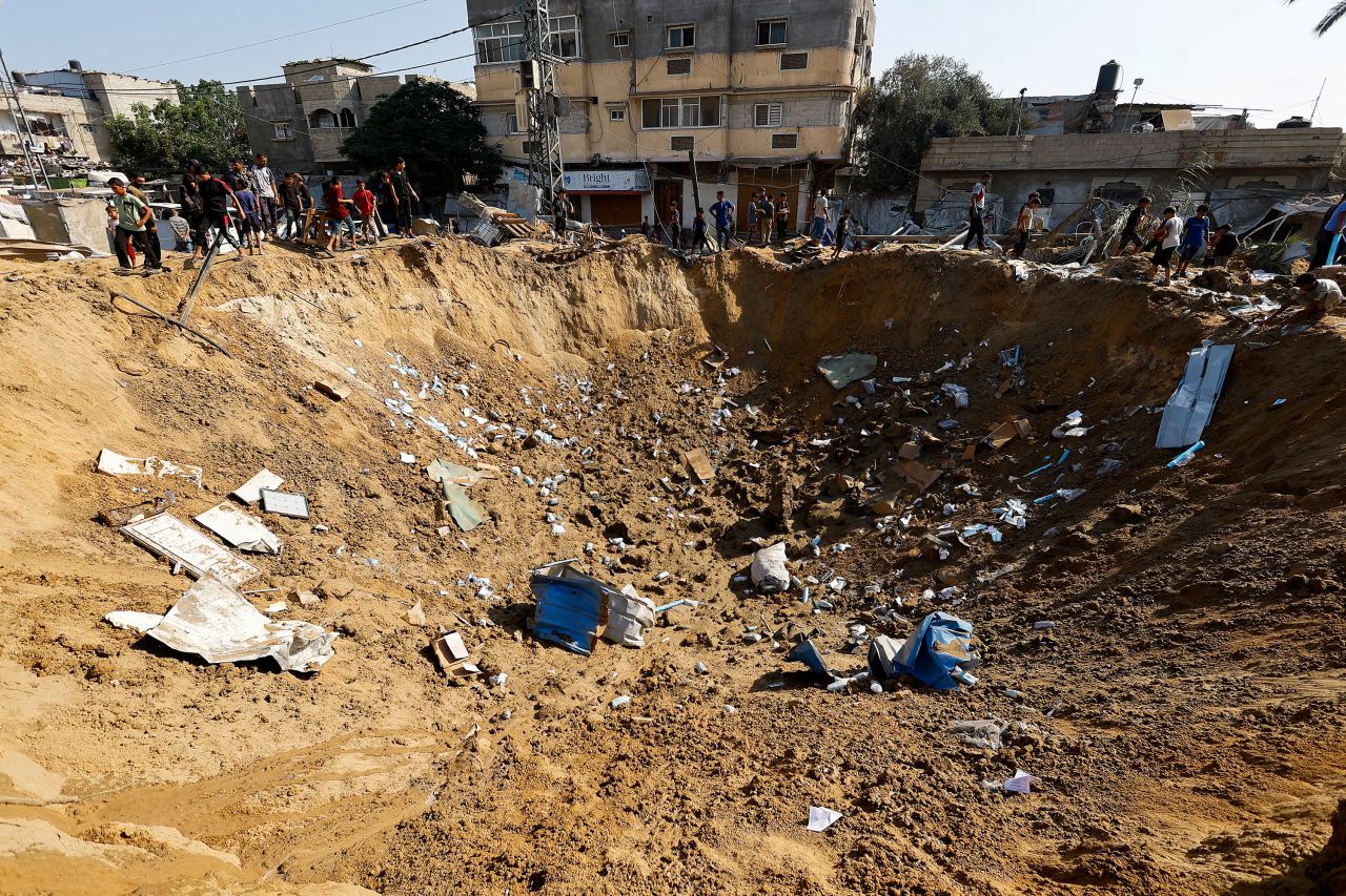 Palestinians stand by a crater, after an Israeli strike in Deir al-Balah, Gaza on Saturday.