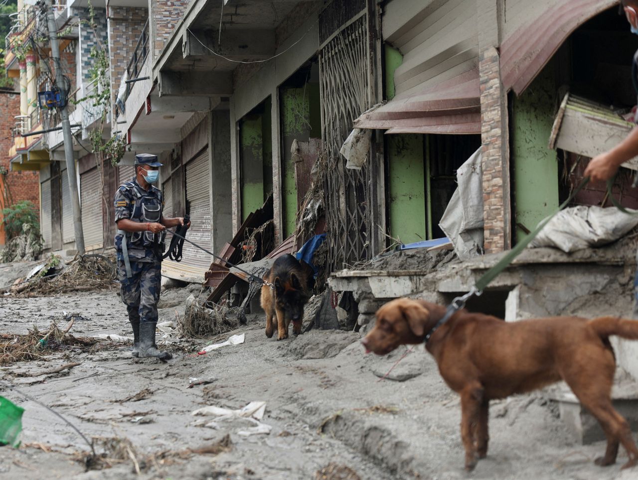 Armed Police Force officials with sniffer dogs look for survivors at the site of flash floods and mudslides in Devighat, Nuwakot district, Nepal, on Saturday.