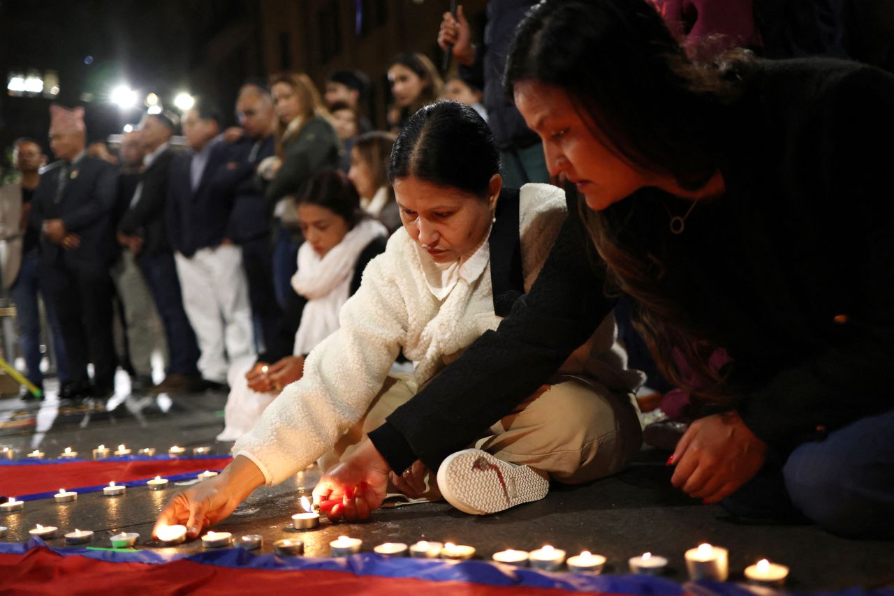 Women lay candles during a vigil for the victims of the Nepal flood in Sydney on Saturday.