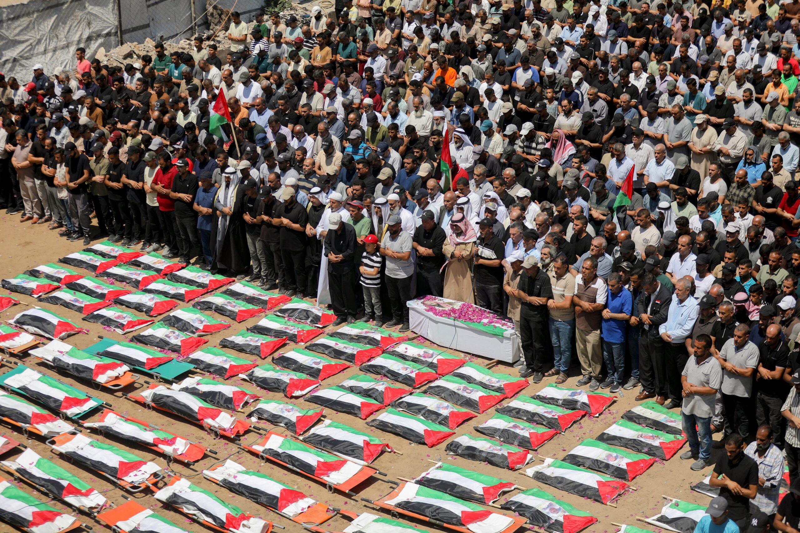 Mourners stand near bodies wrapped in Palestinian flags during a mass funeral in Gaza City, Gaza Strip,