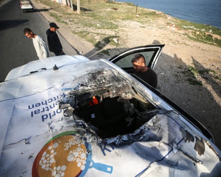 A shot from above showing a vehicle bearing the World Central Kitchen logo on its roof punctured by large, charred hole