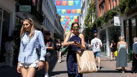 Getty Images two shoppers on a busy shopping street in London walking towards the camera wearing summery clothing