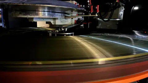 Light shines off the edges of the IMAX 70mm film tightly wound into a reel