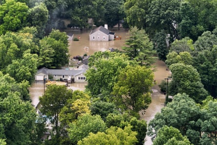 Brown water among trees and houses.