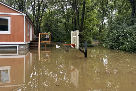 A basketball hoop beside a house underwater nearly to the backboard.