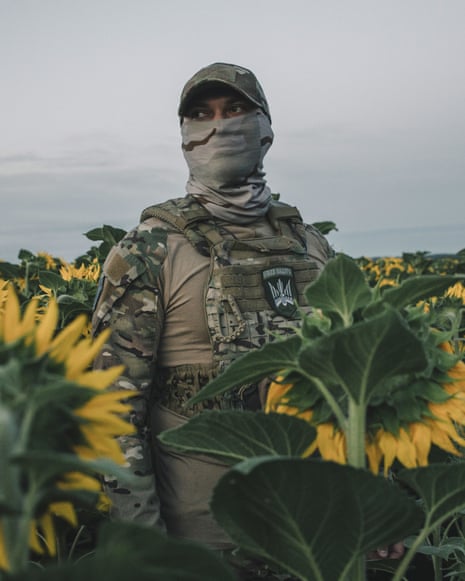 Ray in a sunflower field, wearing a camouflage cap, neck gaiter and military uniform