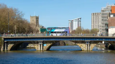 Getty Images A bus travels over a bridge in Bristol with blocks of flats in the background and a river running beneath it