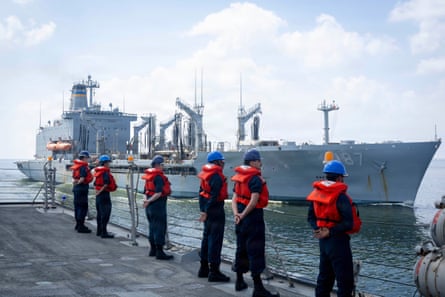 a row of people in life vests standing near water and ships
