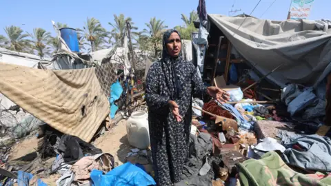 Reuters A Palestinian woman stands amid debris at a tent camp in Khan Younis.