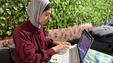 BBC Walaa Volidis, a Palestinian software engineer, works on her laptop in Deir al-Balah, central Gaza