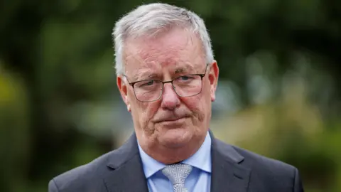 PA Media Mike Nesbitt, a man with grey hair and glasses, grey suit, blue shirt and grey tie.