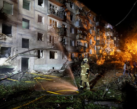 Firefighters work to put out a fire at an apartment building in Kyiv hit by a Russian missile strike