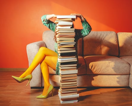 Person with yellow tights reading on sofa behind large stack of books