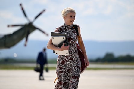 a woman smiles while holding a laptop outside