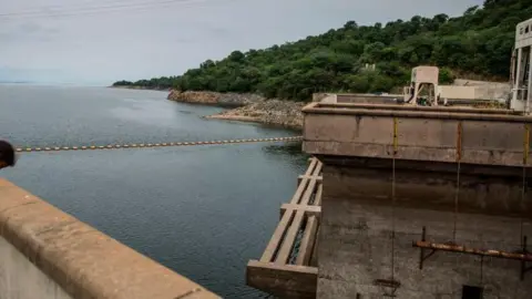 AFP via Getty Images The Kariba dam seen from one of its ridges, overlooking the reservoir and green landscape in the distance