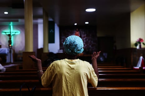 seen from behind, a woman holds up her hands in church