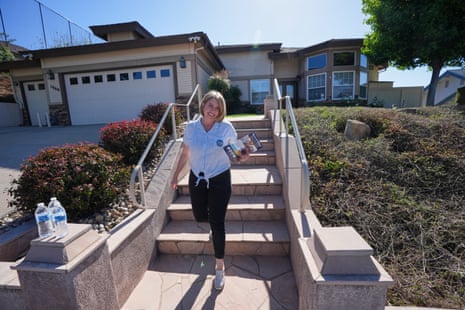 A woman walks away from a house while carrying pamphlets.
