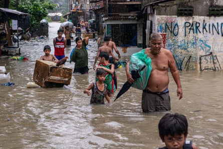 Residents in Barangay Sta Ana in San Mateo, Rizal, the Philippines, evacuate to higher grounds with their belongings