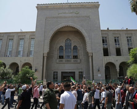 A crowd of people outside a court building of Islamic architectural design