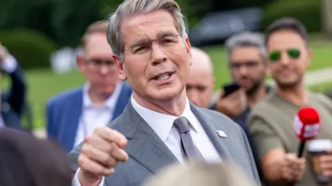 EPA US Treasury Secretary Scott Bessent addresses members of the media on the lawn outside the White House. He's wearing a light grey suit, white shirt and silver tie