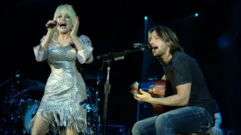 Getty Images Dolly Parton and Keith Urban performing on stage