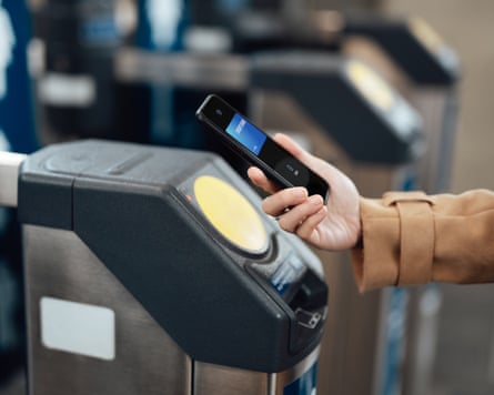 Close-up of a woman paying at a tube station barrier with her smartphone.