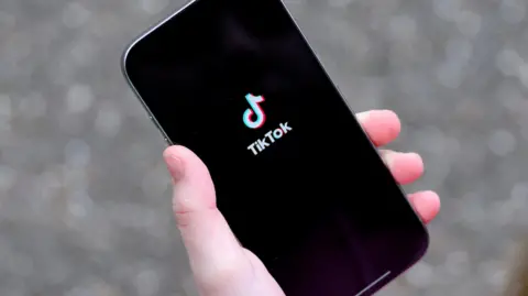 Reuters A young woman holding her iPhone while showing the TikTok app.