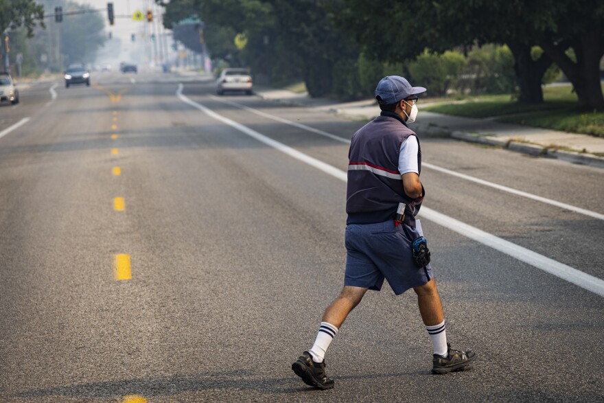 A postal worker walks outside as smoke from Oregon wildfires affects air quality in downtown Boise.