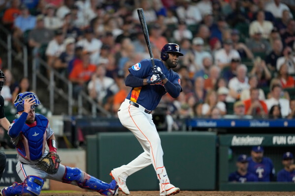 Houston Astros' Yordan Alvarez, right, hits a two-run double as Texas Rangers catcher Austin Wynns watches during the seventh inning of a baseball game Sunday, Aug. 2, 2026, in Houston. (AP Photo/David J. Phillip)