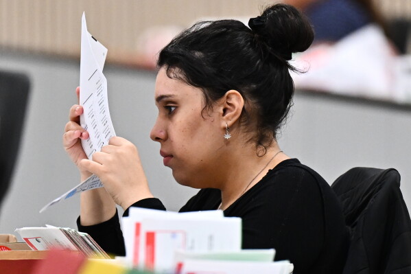 A worker inspects a ballot at the L.A. County Ballot Processing Center during the California primary election on Tuesday, June 2, 2026, in City of Industry, Calif. (AP Photo/William Liang)
