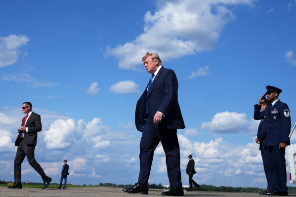 President Donald Trump, center, walks from Air Force One at Morristown Municipal Airport in Morristown, N.J., Friday, July 31, 2026, from Camp David, the presidential retreat. (AP Photo/Jacquelyn Martin)