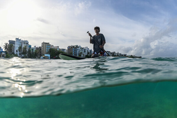 A surfer from Aloha Ufaa Surf Club in Hulhumale participates in an underwater trash clean up session with Ripple, a youth group, off the coast of Hulhumale, Maldives, June 27, 2026. (AP Photo/Sophia Nasif)