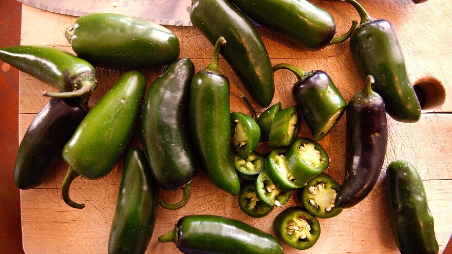 Jalapeno peppers sit on a cutting block.