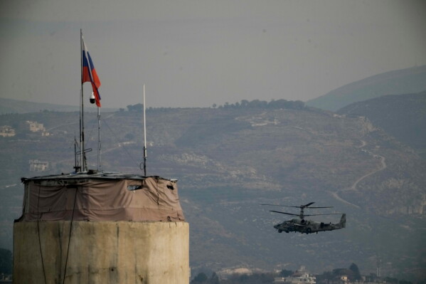 A Russian helicopter flies over the Hmeimim Air Base located southeast of the city of Latakia in the town of Hmeimim, Syria, Dec. 16, 2024. (AP Photo/Leo Correa, File)